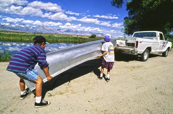 Pojkar laddar kanot i lastbil. — Stockfoto