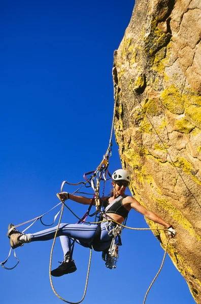 Bir uçurum için sıkı bir kadın dağcı. — Stok fotoğraf