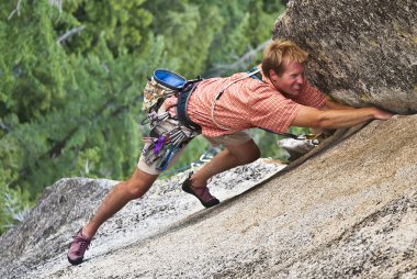 Rock climber clinging to a cliff. clipart