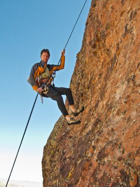 Rock climber rappelling. clipart