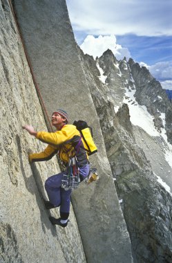 Rock climber clinging to a cliff. clipart