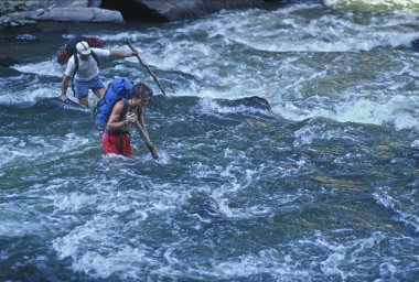 Hikers crossing a river. clipart