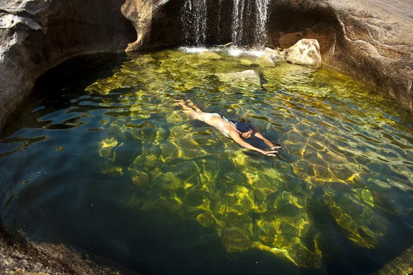 Frau schwimmt in einem natürlichen Pool. — Stockfoto