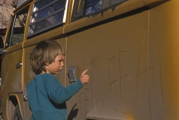 Boy writing on a car. — Stock Photo, Image