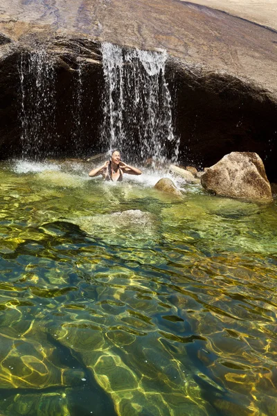Vrouw in een natuurlijke zwembad zwemmen. — Stockfoto