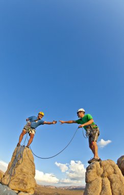 Rock climbing team reaching the summit. clipart