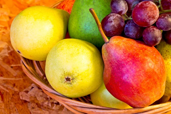 stock image Yellow, red and green pears with red grapes in woven baskets