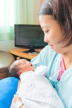Asyalı kadın annesinin kollarında dikey yeni doğan