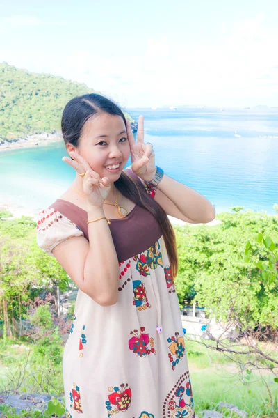 Aziatische vrouw met twee vingers op de zee — Stockfoto