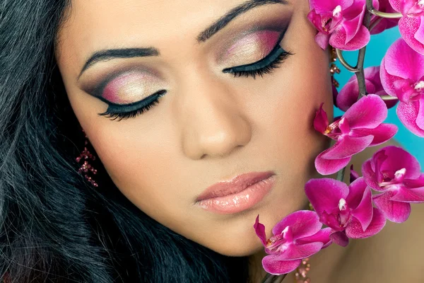 Güzel genç kadının yüzüne orkide çiçekleri ile — Stok fotoğraf
