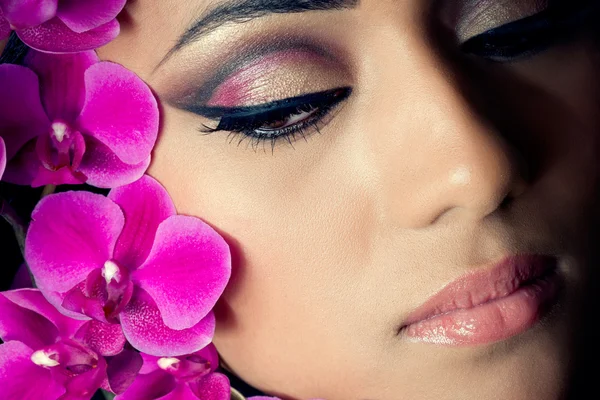 Güzel bir kadının yüzüne orkide çiçekleri ile portre çekim