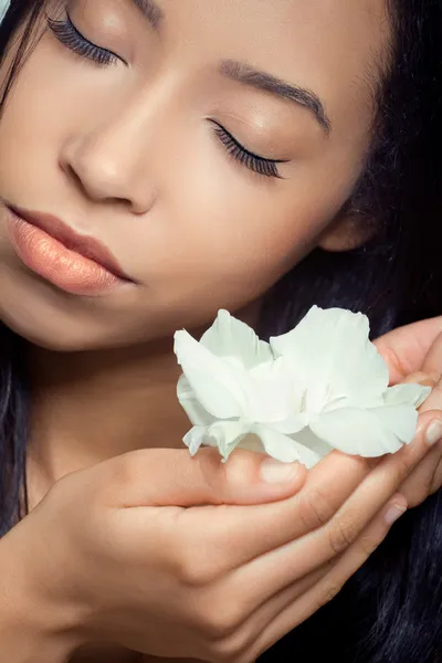 Mooie jonge vrouw die een witte bloem in de buurt van haar gezicht — Stockfoto