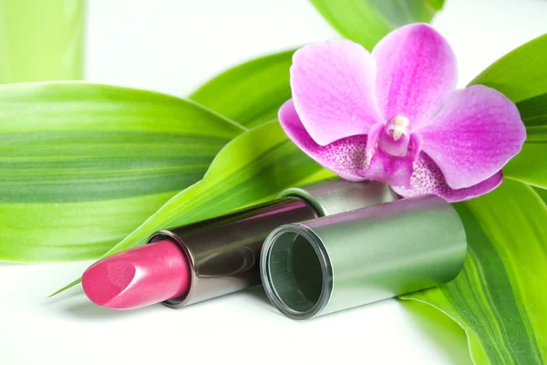 Natural cosmetics concept: a lipstick with bamboo leaves and an — Stock Photo, Image