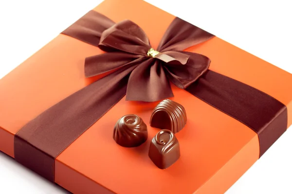 Milk chocolates and beautiful gift box with ribbon bow, closeup — Stock Photo, Image