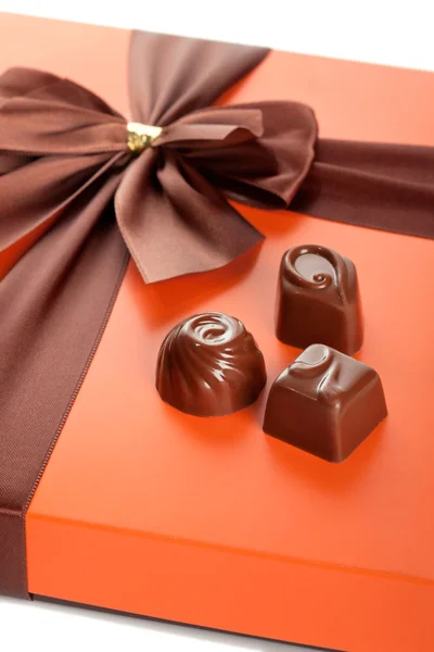 Chocolates con leche y hermosa caja de regalo con lazo de cinta, primer plano —  Fotos de Stock