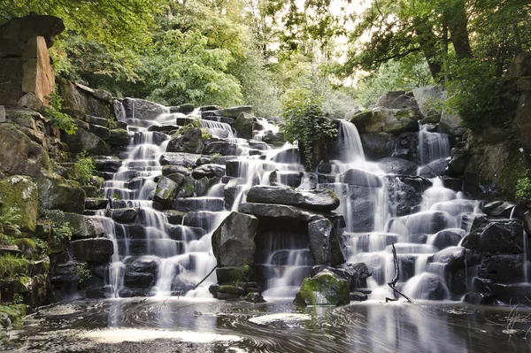 stock image Beautiful waterfall cascades over rocks in lush forest landscape