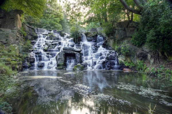 stock image Beautiful waterfall cascades over rocks in lush forest landscape