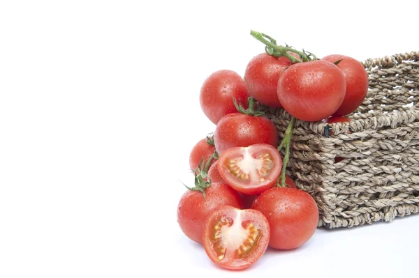 Fresh ripe vine tomatoes in rustic basket with sliced tomato iso — Stock Photo, Image
