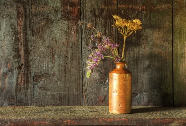 Natura morta stile retrò di fiori secchi in vaso contro corteggiamento indossato Foto Stock Royalty Free