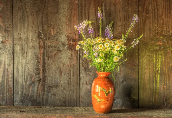 Natura morta stile retrò di fiori secchi in vaso contro corteggiamento indossato Immagine Stock