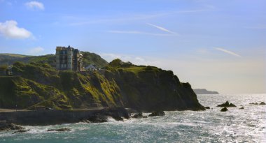 Fairytale chateau atop seaside cliffs on bright sunny day clipart