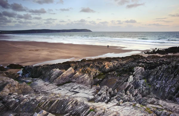 Pareja solitaria caminando a lo largo de la impresionante playa durante los soles vibrantes —  Fotos de Stock