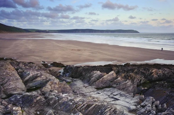 Pareja solitaria caminando a lo largo de la impresionante playa durante los soles vibrantes — Foto de Stock