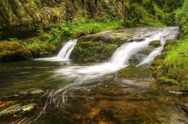 Lenyűgöző vízesés folyik át sziklák, buja zöld erdőben — Stock Fotó