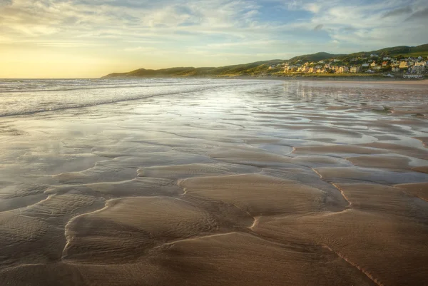 Vista lungo la spiaggia al tramonto come marea va fuori rivelando modelli i — Foto Stock