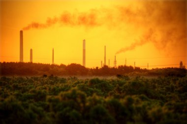 Industrial chimney stacks in natural landscape polluting the air clipart