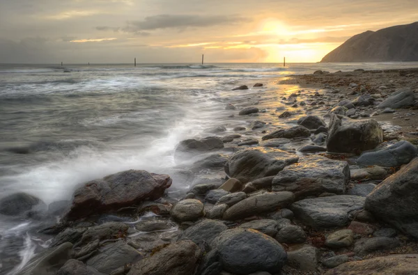 stock image Beautiful warm vibrant sunrise over ocean with cliffs and rocks