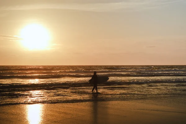 Surfista femminile con silhouette da tavola da surf contro un tramonto mozzafiato — Foto Stock