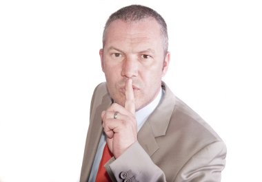 Middle aged businessman in suit makes gesture to be quiet clipart