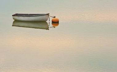 Solitary rowing boat and buoy on sea with sunset reflected in ri clipart