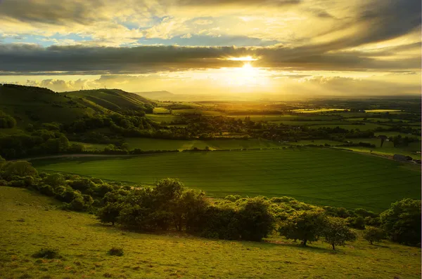 Stunning countryside landscape with sun lighting side of hills a — Stock Photo, Image