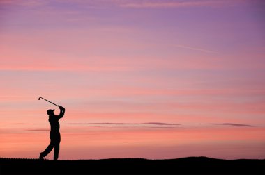 Golfer silhouette against stunning sunset sky clipart