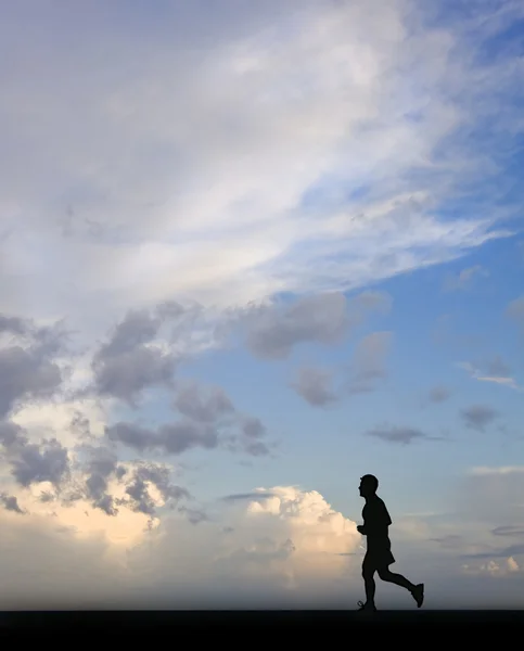 Silhueta de corredor masculino único contra o céu azul deslumbrante — Fotografia de Stock