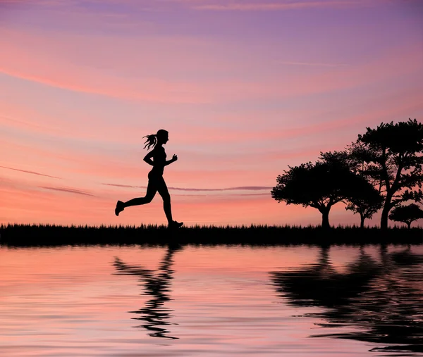 Female jogger silhouette against stunning colorful sunset sky an — Stock Photo, Image