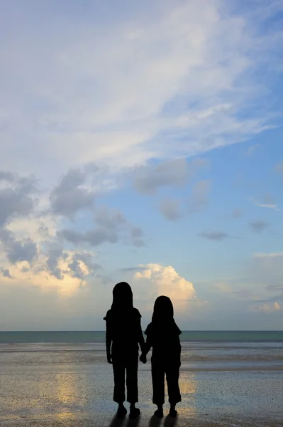 Silhouette bambini vulnerabili sulla spiaggia al tramonto — Foto Stock