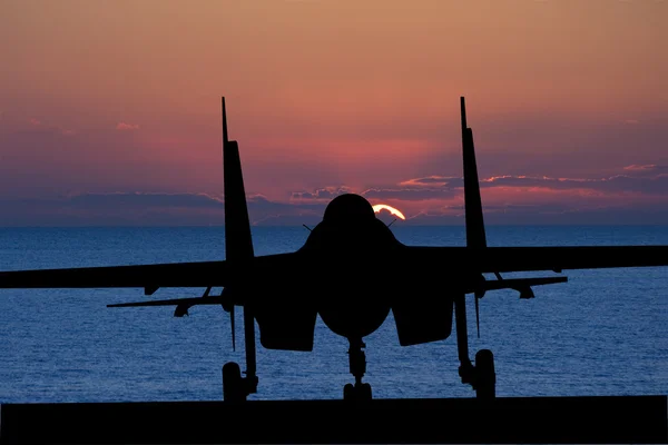 Silhouette of military attack aircraft against vibrant sunset sk — Stock Photo, Image