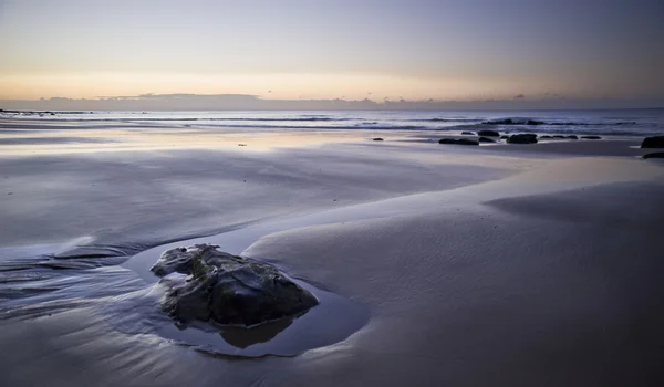 Hermosa vista de la playa al amanecer con detalles rocosos —  Fotos de Stock