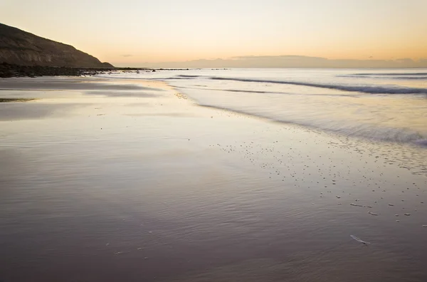 Hermosa vista de la playa al amanecer con detalles rocosos —  Fotos de Stock