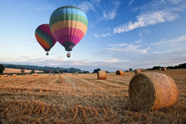 Balões de ar quente sobre fardos de feno paisagem pôr do sol — Fotografia de Stock