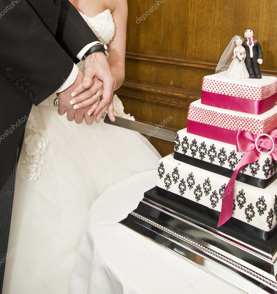 Detail of bride and groom cutting wedding cake