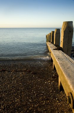 ahşap groyne iskelesi ile pürüzsüz deniz üzerinde huzurlu gündoğumu