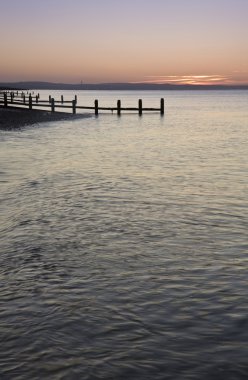 ahşap groyne iskelesi ile pürüzsüz deniz üzerinde huzurlu gündoğumu