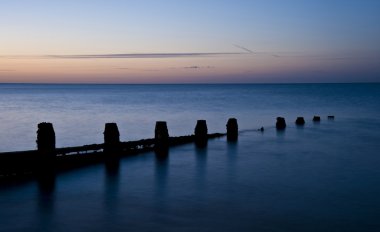 ahşap groyne iskelesi ile pürüzsüz deniz üzerinde huzurlu gündoğumu