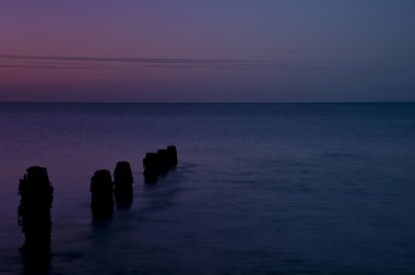 ahşap groyne iskelesi ile pürüzsüz deniz üzerinde huzurlu gündoğumu