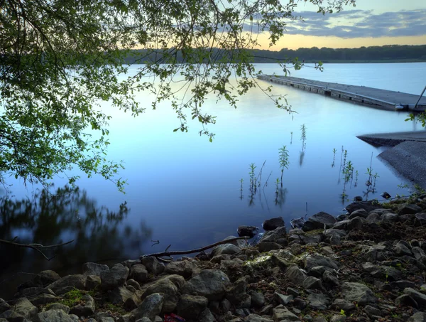 Długi, drewniany pomost molo w spokojne jezioro podczas zachodu słońca latem — Zdjęcie stockowe