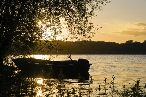 Canlı yaz gün batımı sırasında sakin göl kenarında balıkçı teknesi — Stok fotoğraf